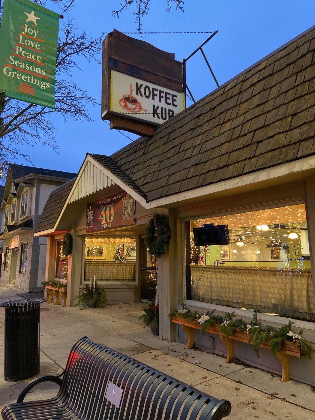 The Koffee Kup storefront at dusk with its vintage hanging sign and warm window light